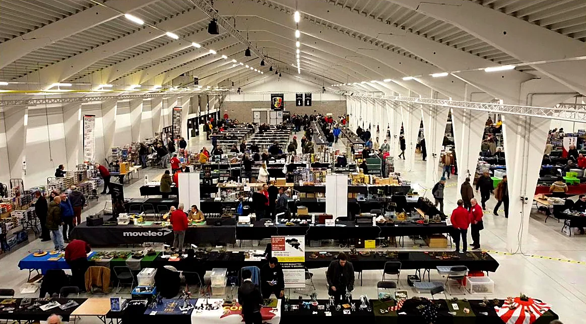 Des visiteurs parcourent les tables des commerçants dans la halle d’exposition