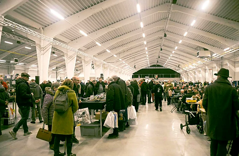 Des visiteurs avec des sacs entre les tables des commerçants